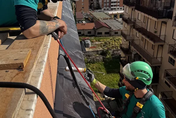 operaio applica silicone in alta quota sospeso con le corde